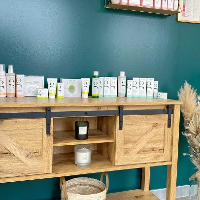 Produits de beauté alignés sur une commode en bois foncé avec des bougies.